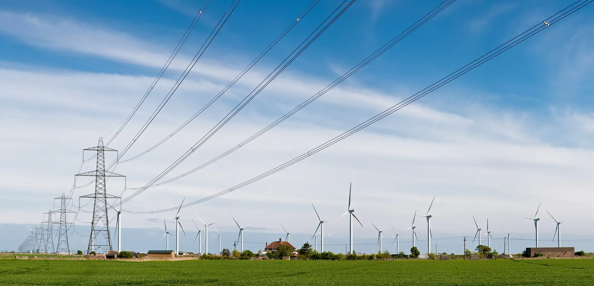 Pylons and onshore wind turbines in a green field