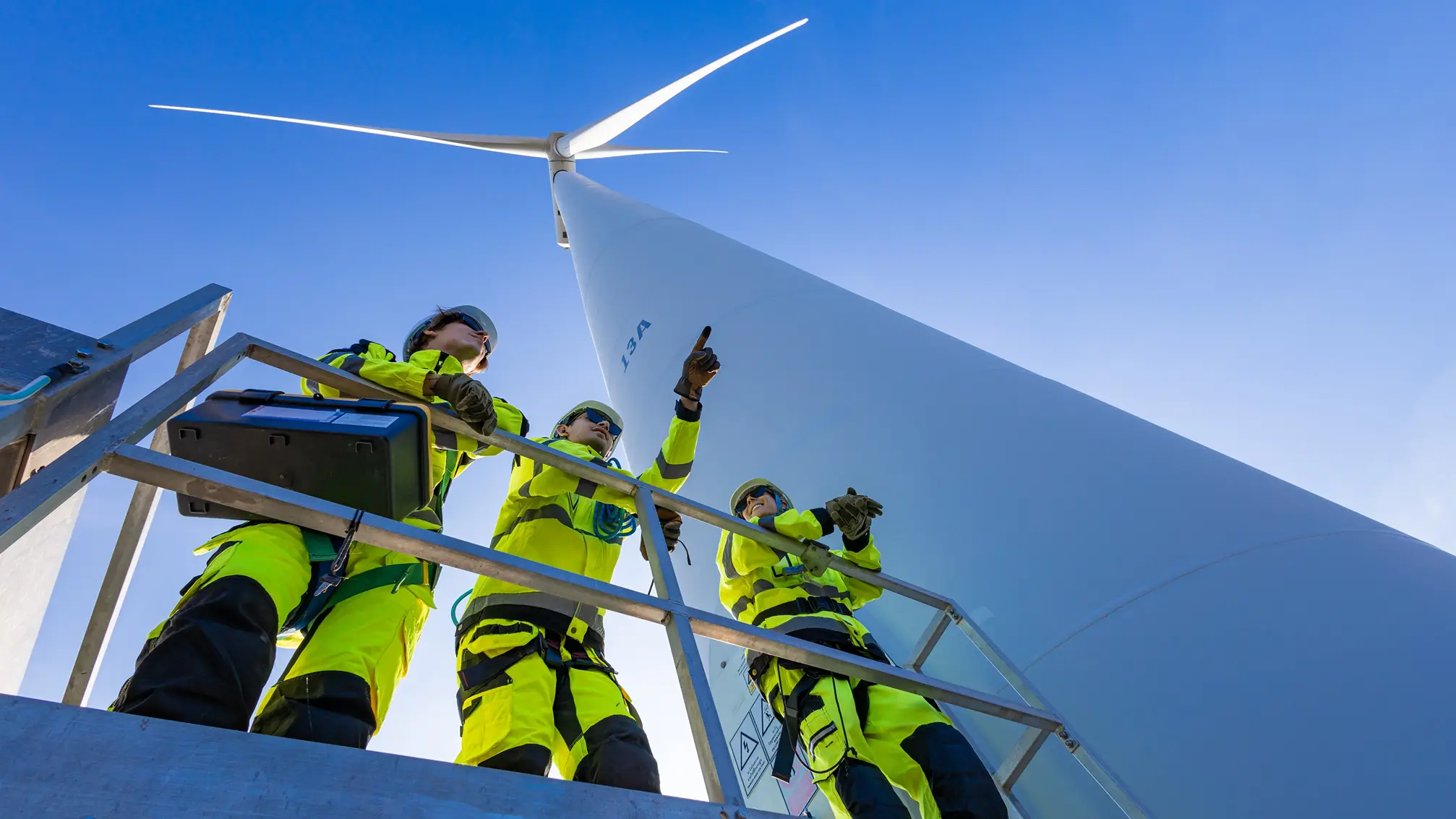 Engineers standing beneath a wind turbine