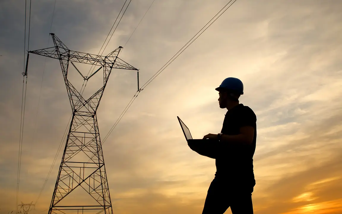 An engineer examining a pylon in the distance