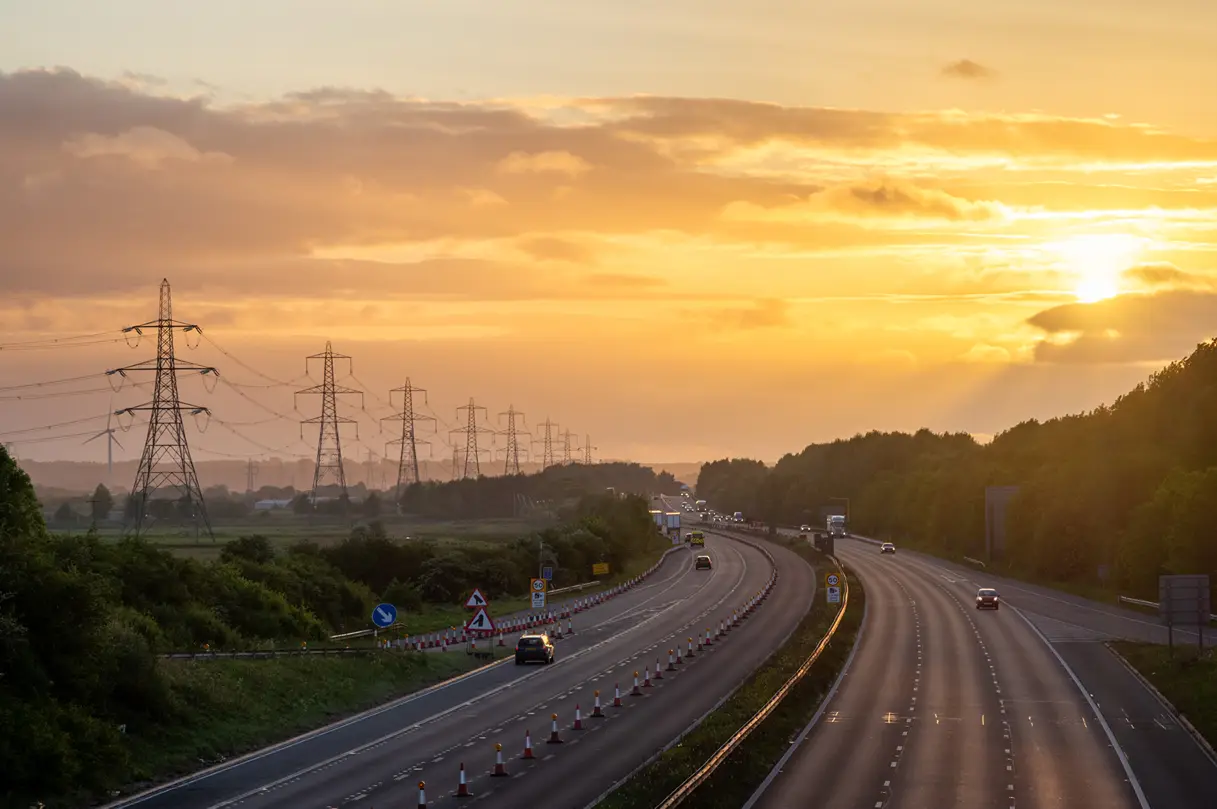 A row of pylons on a motorway at sunset