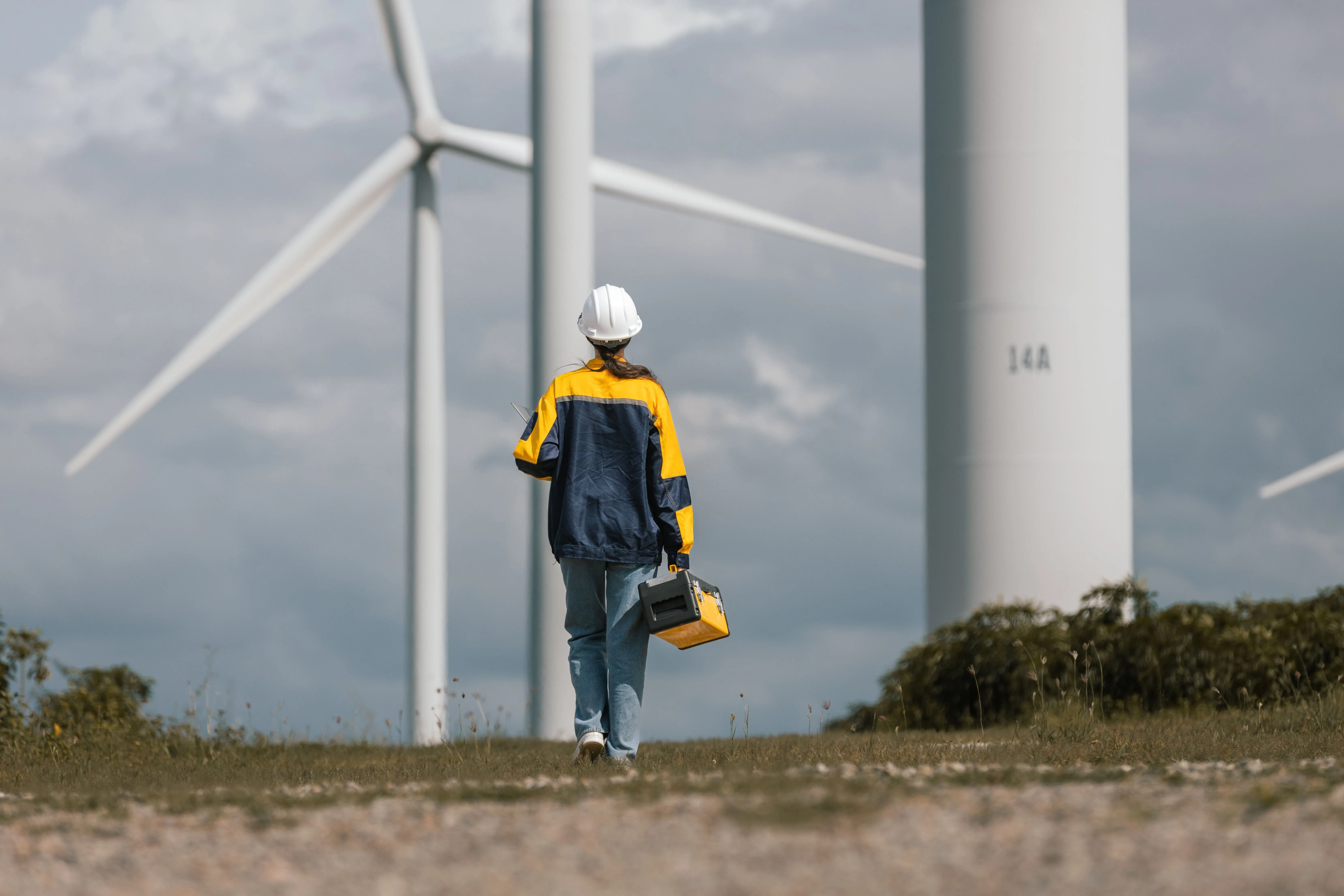 Wind Turbine Technician Walking Towards A Turbine