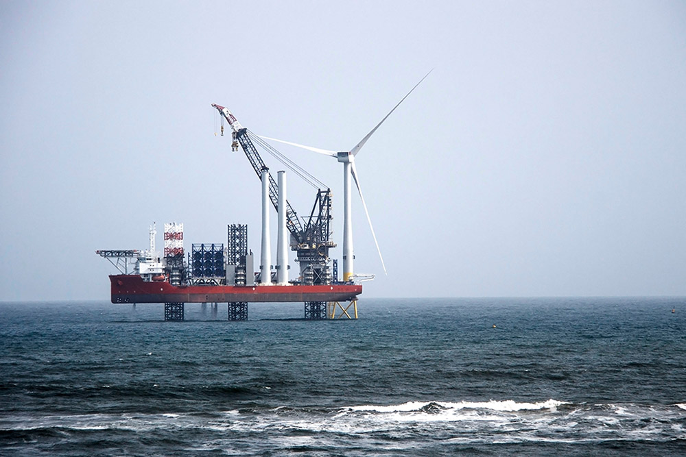 A large vessel assembling an offshore wind turbine